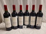 six bottles of red wine are lined up on a table