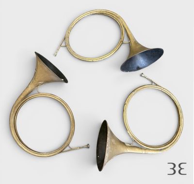 trois instruments de musique en laiton disposés en cercle sur une surface blanche