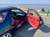 une voiture noire dont une portière rouge est ouverte dans la rue