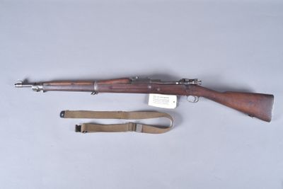 un vieux fusil avec un canon en bois et une bretelle, posé sur une table