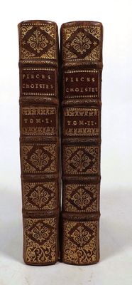 two old books sitting on top of each other on a white surface
