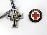 two medals and a medal on a white surface with a red cross in the center