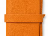 a small orange leather journal with a strap around it