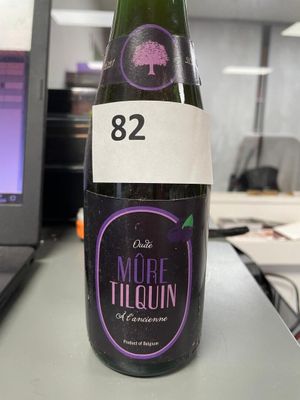 a bottle of liquor sitting on a table in front of a laptop
