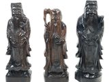 three carved figurines of men with hats and beards