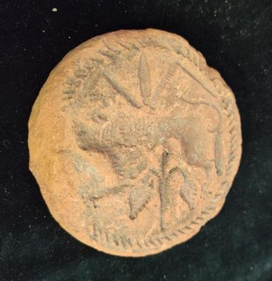 an old coin with a bird on it sitting on a black surface