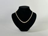 collier de perles présenté sur un mannequin devant un fond blanc