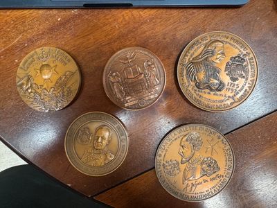 several coins sitting on top of a wooden table next to a laptop