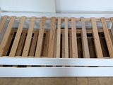 a white bed frame with wooden slats on it