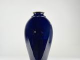 a blue vase with a gold rim sitting on a white surface