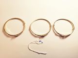 three gold rings and a pair of scissors on a white surface