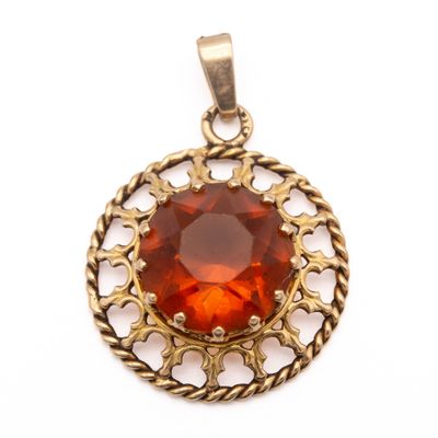 a close up of a pendant with a red stone in it