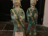 two asian figurines sitting on a stone floor