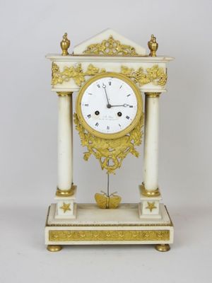 a white and gold clock sitting on top of a table