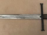 a close up of a knife on a brown surface with a black handle