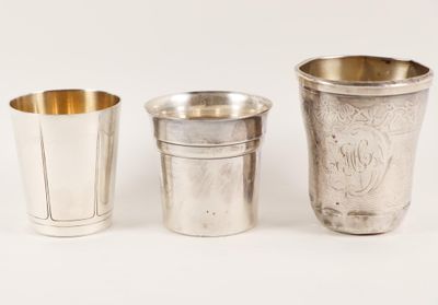 trois coupes en argent sont alignées les unes à côté des autres sur une surface blanche