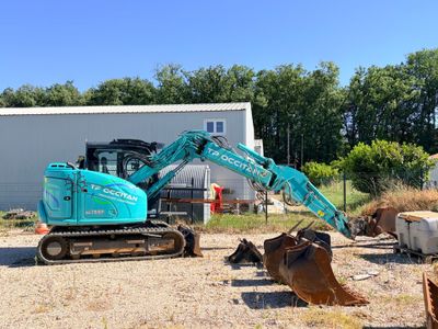 une pelleteuse bleue qui est à l'arrêt dans la terre