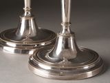 two silver candlesticks sitting on top of each other