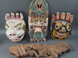trois masques en bois sont posés les uns à côté des autres sur une surface grise