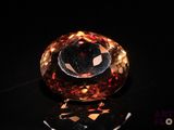 a close up of an orange diamond on a black surface