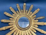 un miroir doré en forme d'étoile rayonnante sur un fond bleu