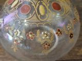a glass vase that has a gold and red design on it