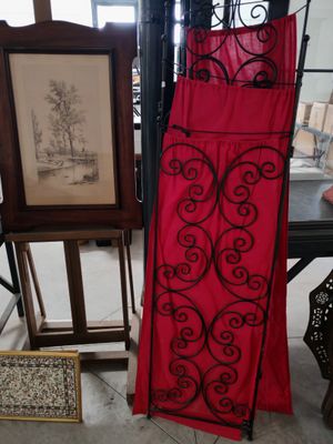 une robe rouge suspendue à un portant à côté d'un tableau