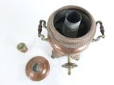 un petit pot en cuivre contenant une bougie