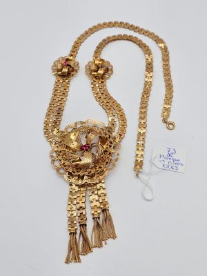 a close up of a gold necklace with a red stone on it