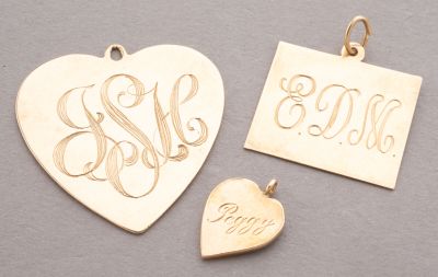 two gold heart shaped pendants with initials and a small heart