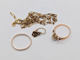 two gold rings, a chain, and a ring on a white surface