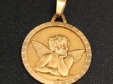 un gros plan d'une médaille d'or sur laquelle figure un ange