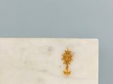 un gros plan d'une dalle de marbre blanc sur laquelle est gravée une croix dorée