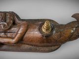a wooden sculpture of a woman laying on a bed