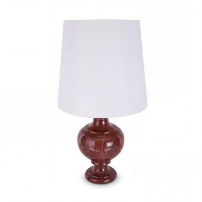 une lampe de table rouge surmontée d'un abat-jour blanc
