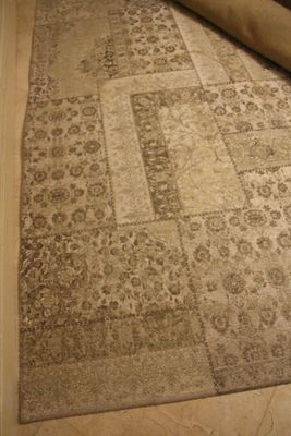 un tapis posé à même le sol, avec un rouleau de moquette à côté
