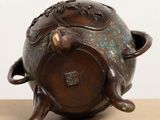 an image of a small bronze pot with a lid on a table