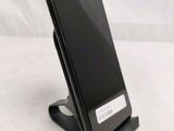 a black cell phone sitting on a stand on a table
