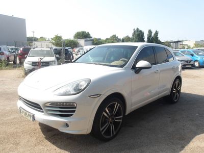 La Porsche Cayenne blanche est garée sur un parking avec d'autres voitures.