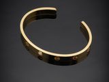 a gold cuff bracelet with the word love engraved on it