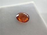 a close up of an orange sapphire stone on a white surface
