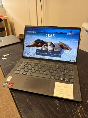 un ordinateur portable posé sur un bureau, sur lequel se trouve un bout de papier