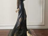 a figurine of a woman in a black dress on a wooden table