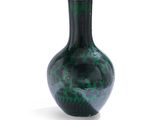 un vase vert posé sur une surface blanche