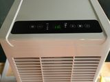 a white air conditioner sitting on top of a wooden table