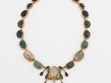 a gold necklace with blue and green stones on it
