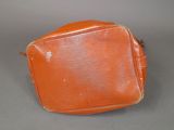 an orange leather bag sitting on top of a gray surface