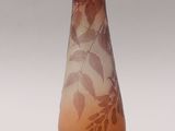 a brown vase with leaves on it sitting on a table