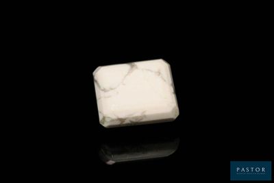 bloc de marbre blanc posé sur une surface noire, avec un fond noir