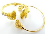 deux bracelets en or ornés de breloques en forme de poisson, posés sur un fond blanc